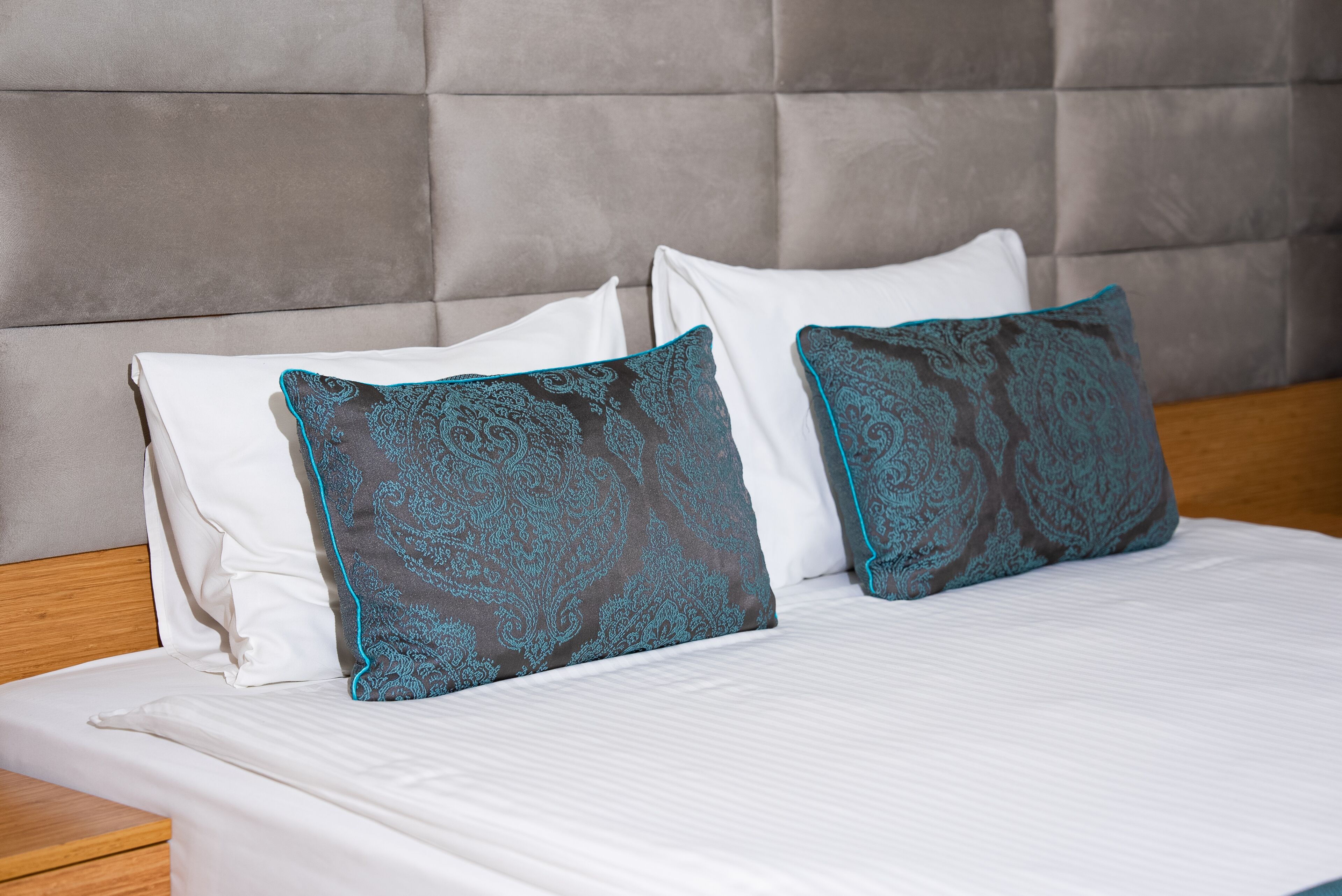 Un lit avec du linge de lit blanc et deux coussins décoratifs à motifs cachemire.