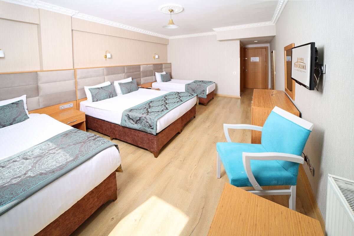 A hotel room with three beds, a desk, and a chair.