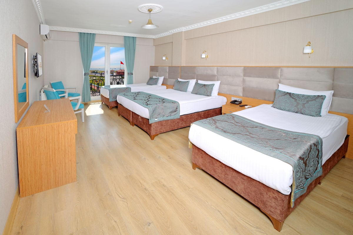 A hotel room with two beds, a desk, and a balcony with a view.