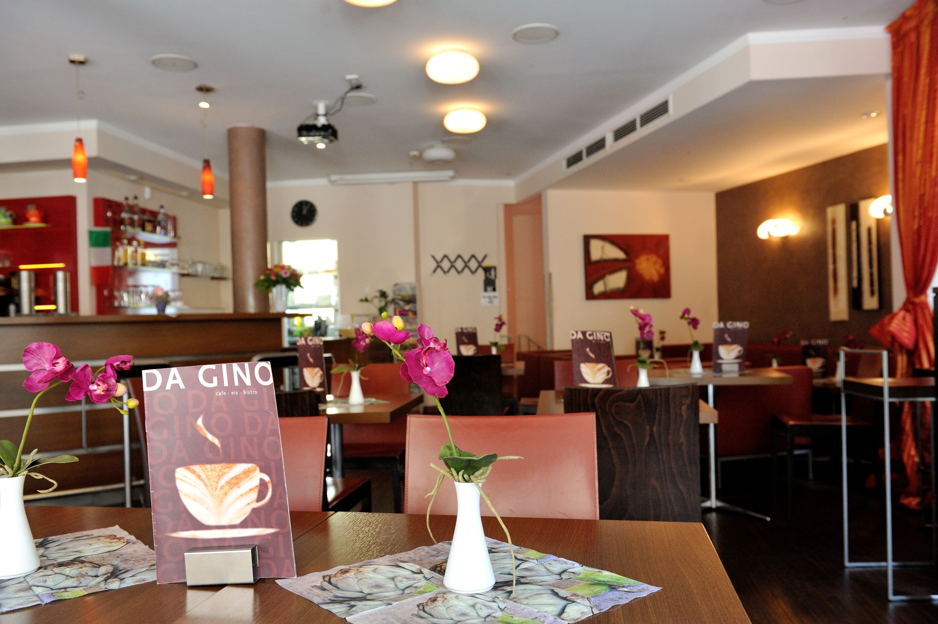 A restaurant interior with tables set for dining, a menu stand, and a bar area.
