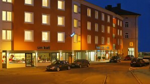 Un hotel de varios pisos con una tienda en la planta baja y un café-bar.