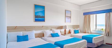 Habitación de hotel con tres camas, un ventanal con vistas y un cuadro en la pared.