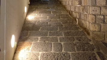 Una scala di pietra conduce su una collina, con un muro in mattoni su un lato e un edificio bianco sull'altro.