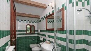 Un baño con azulejos verde y blanco, un lavabo, un inodoro y una ducha.