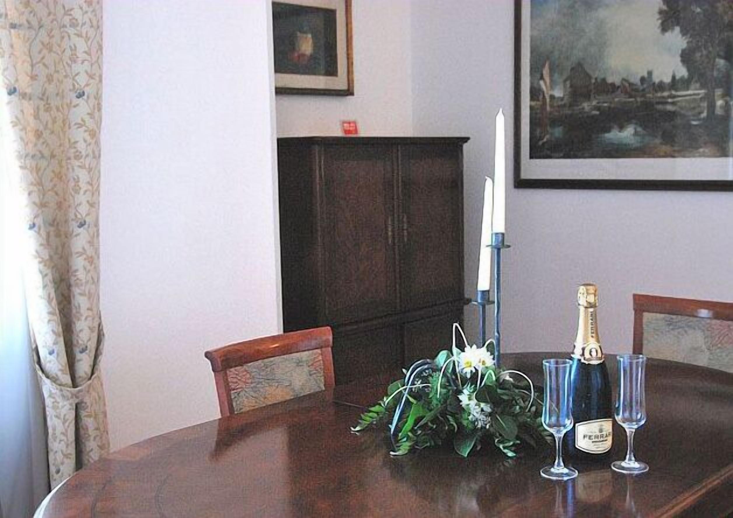A dining table with a floral centerpiece, a bottle of champagne, and four glasses.