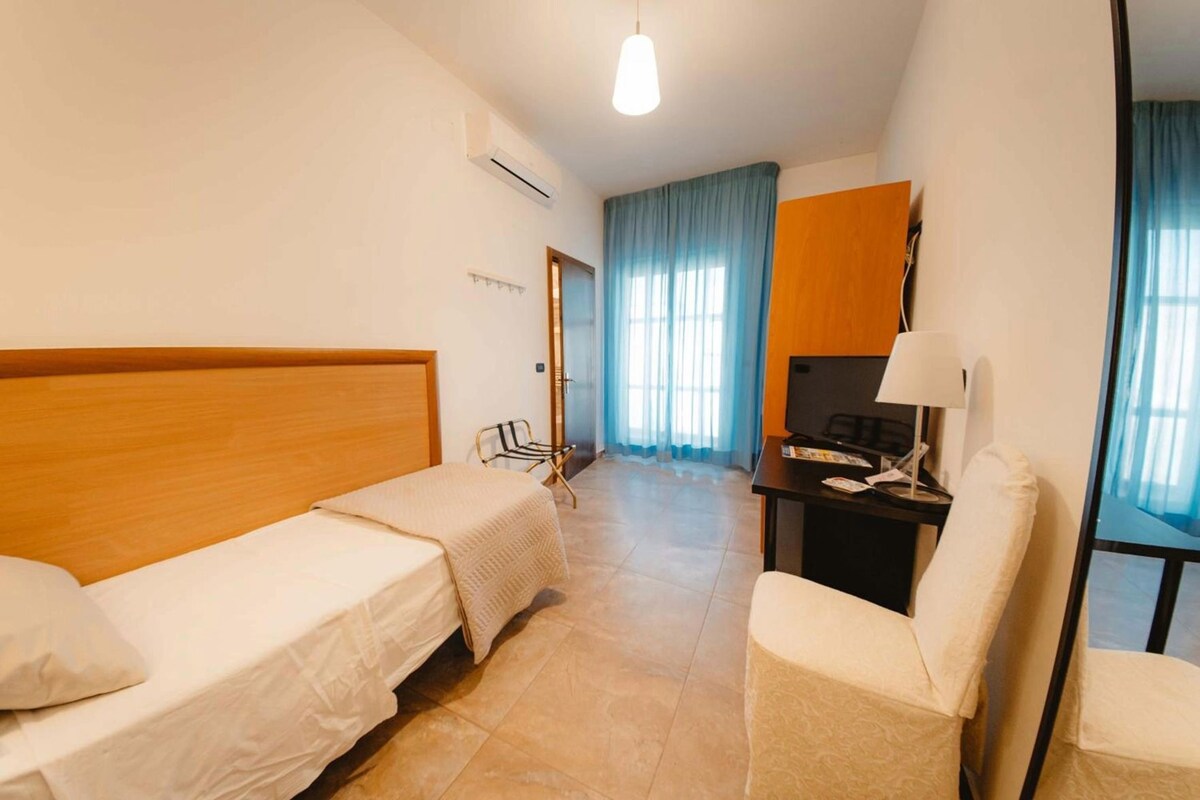 Une chambre d’hôtel avec un lit, un bureau, une chaise et un téléviseur.