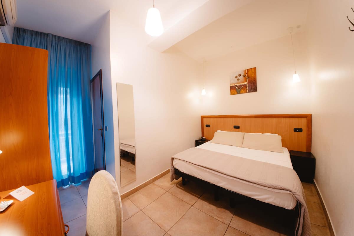 Een hotelkamer met een bed, nachtkastjes, een bureau en een stoel.