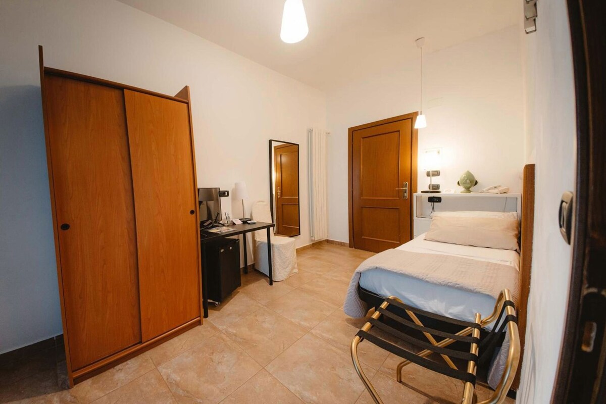 Une chambre d’hôtel avec un lit, un bureau, une chaise et une armoire.