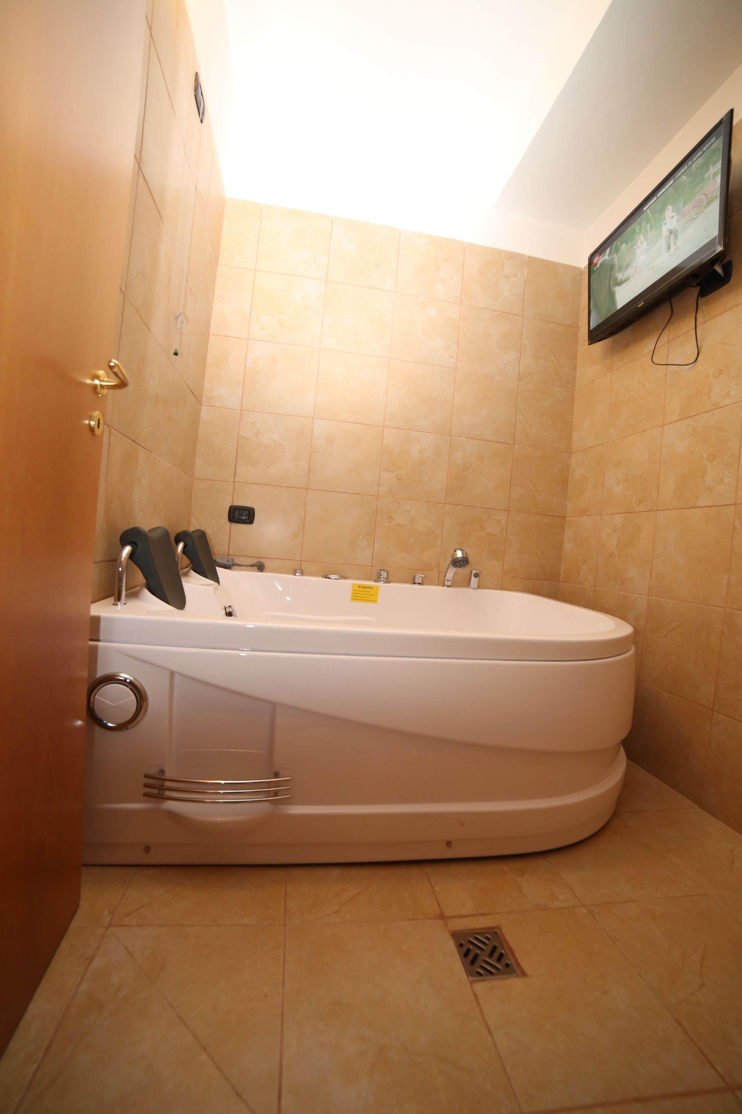 Une salle de bain moderne avec une grande baignoire, un téléviseur fixé au mur et une pomme de douche.