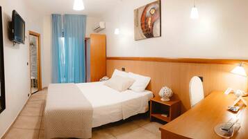 A hotel room with a bed, bedside table, desk, chair, and a television on the wall.