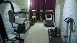 Een fitnessruimte met trainingsapparatuur, waaronder een loopband, elliptische trainer en gewichtstoestellen.