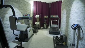Un gimnasio con equipo de ejercicio, que incluye una cinta de correr, una elíptica y máquinas de pesas.