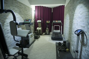 Uma sala de ginástica com equipamentos de exercício, incluindo esteira, elíptico e aparelhos de musculação.