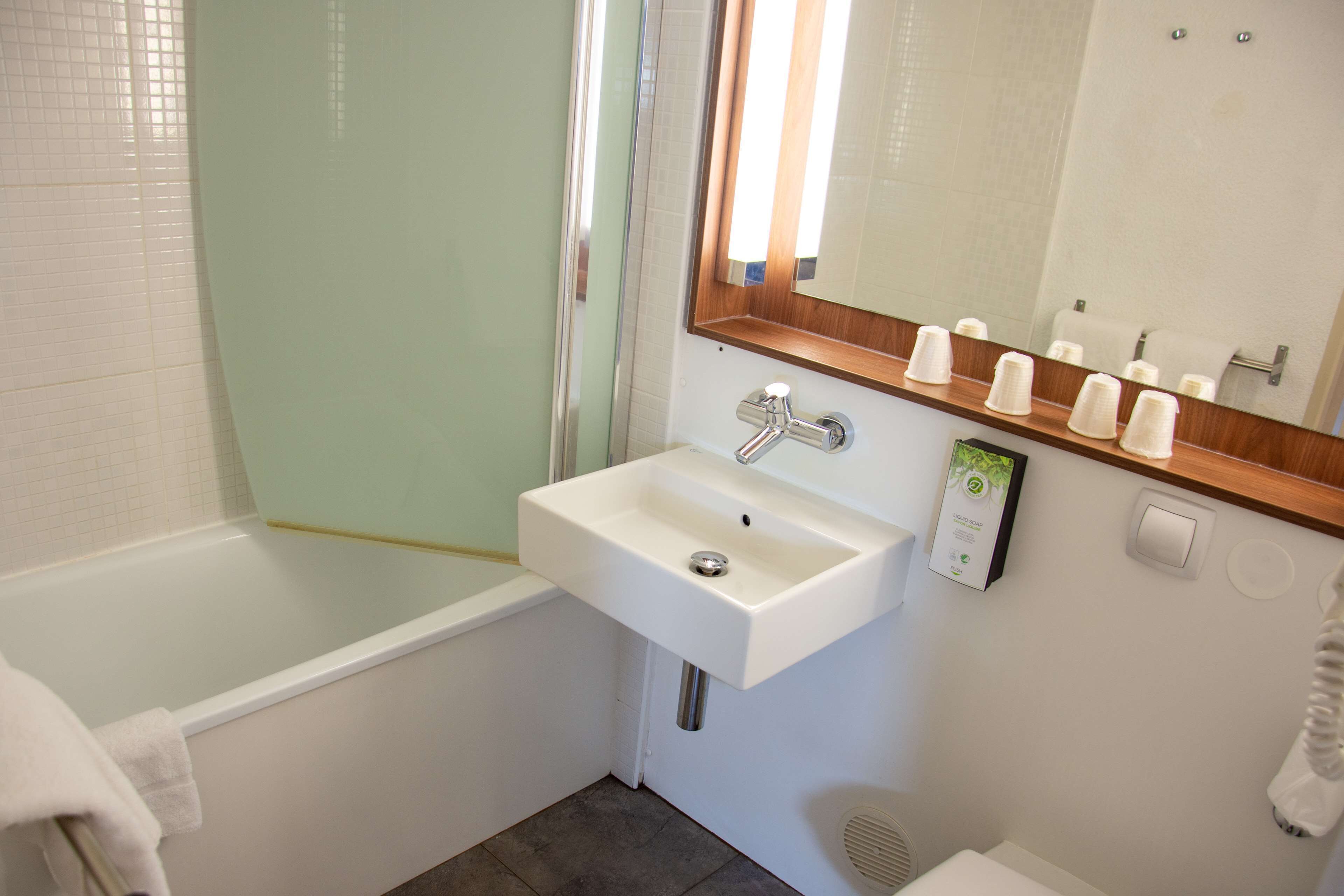 Un baño con un lavabo blanco, un espejo y una ducha.