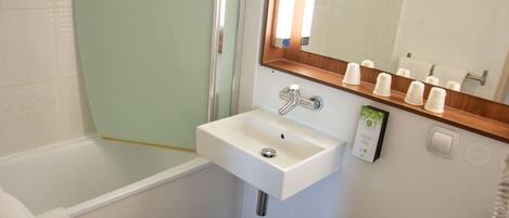 Un baño con un lavabo blanco, un espejo y una ducha.