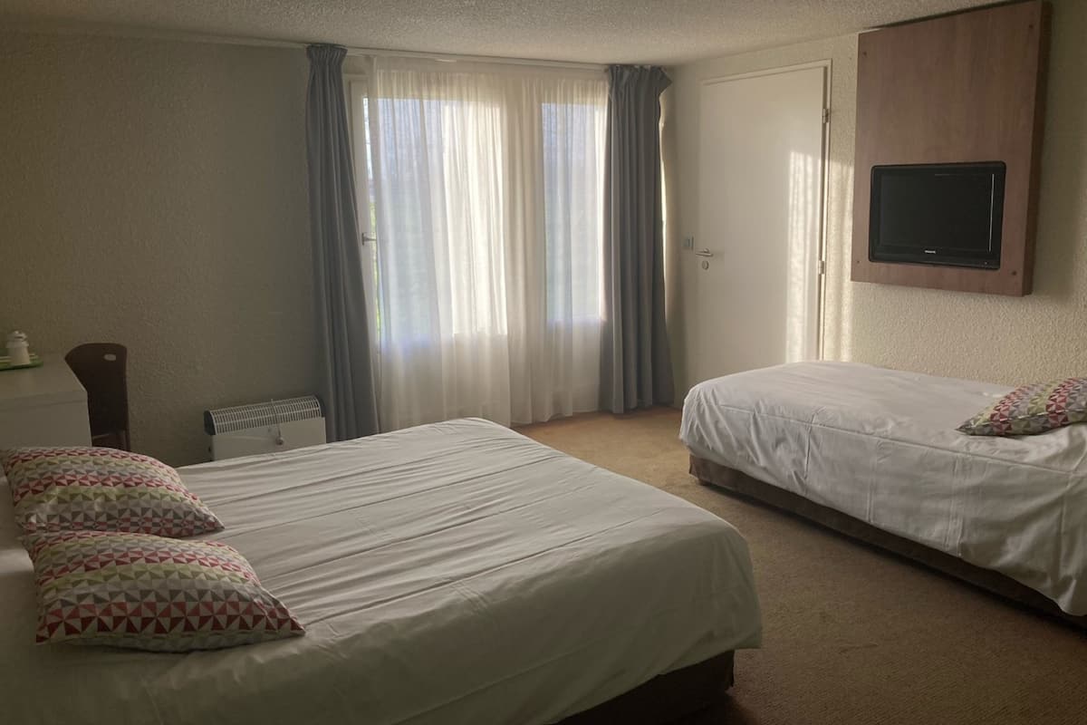 Une chambre d’hôtel avec deux lits, un téléviseur fixé au mur et un radiateur.