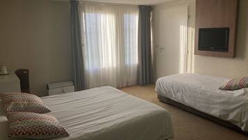A hotel room with two beds, a TV mounted on the wall, and a radiator.