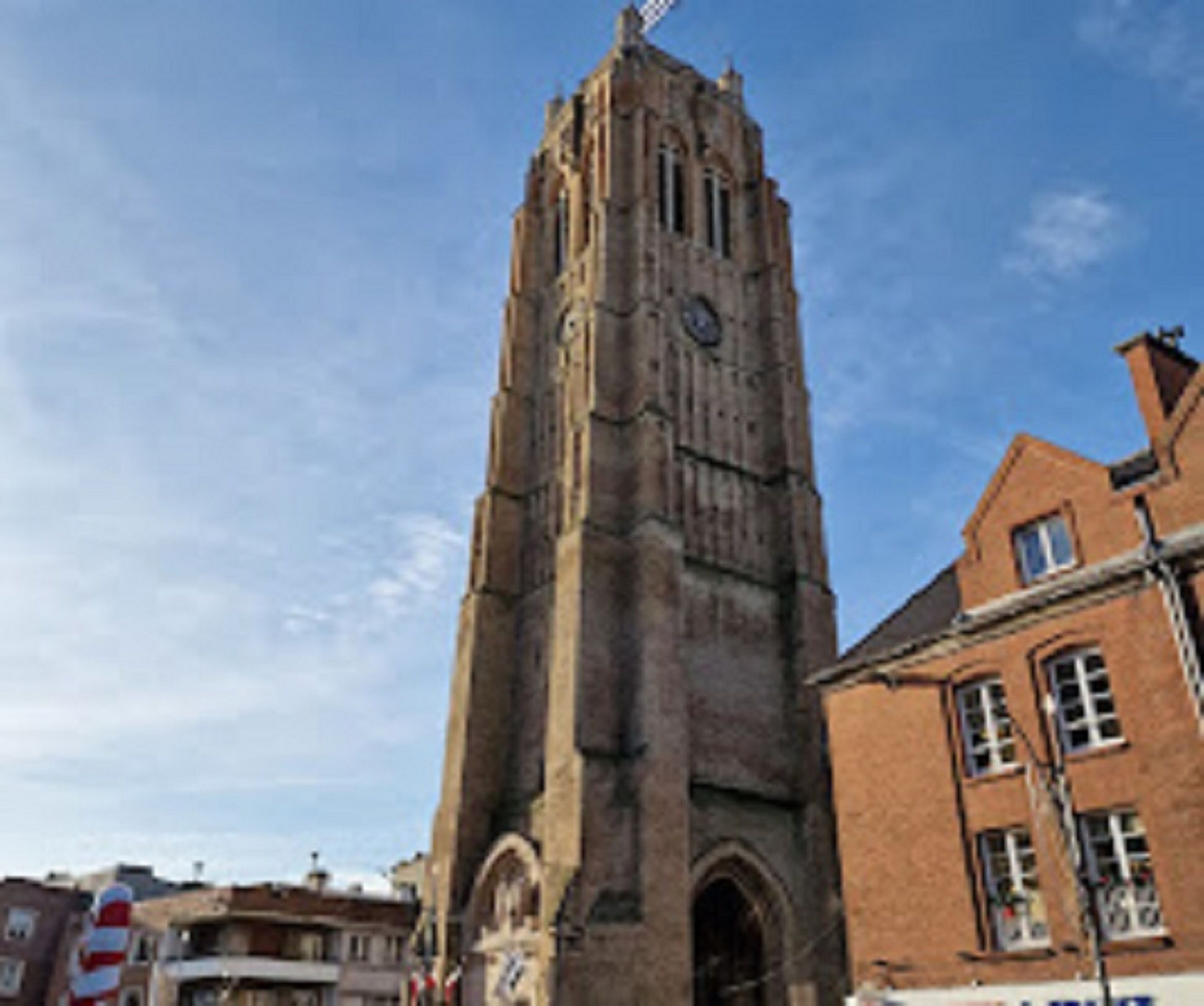 Eine hohe, historische Kirche mit einem Glockenturm, umgeben von traditionellen Gebäuden.