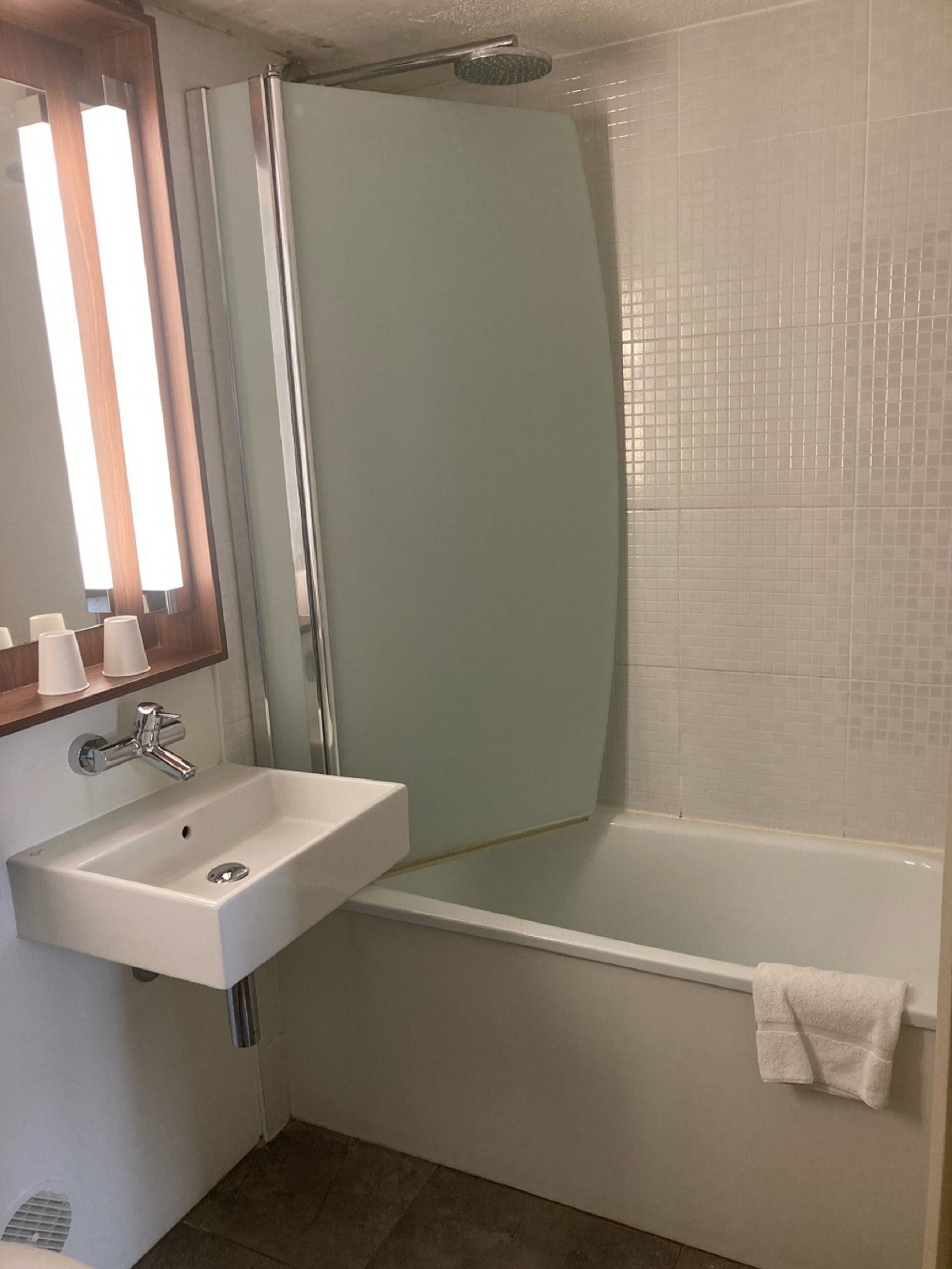 A bathroom with a white sink, a glass shower enclosure, and a white bathtub.