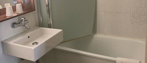 Un baño con un lavamanos blanco, una cabina de ducha de vidrio y una bañera blanca.