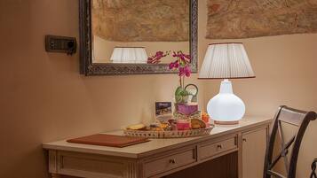 A hotel room with a vanity, a mirror, a lamp, a chair, and a tray with breakfast items.