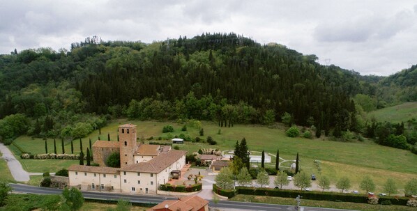 Un village rural avec une église imposante dotée d’un clocher, entouré d’une végétation luxuriante et avec une colline en arrière-plan.