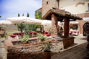 Un patio al aire libre con paredes de ladrillo, suelo de piedra y mesas con manteles rojos.