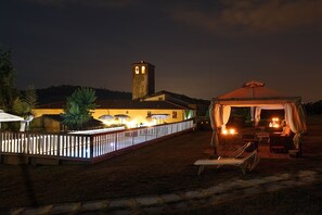 Un bâtiment doté d’une tour, avec des tables à l’extérieur, protégées par des parasols, et une tente.