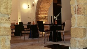 Uma sala de jantar com um arco de pedra, uma mesa com cadeiras e um vaso com flores.