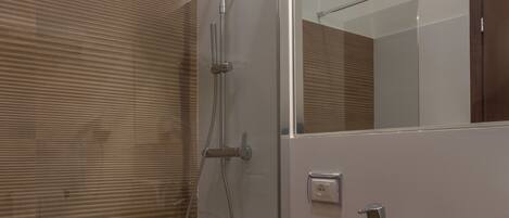 A modern bathroom with a glass-enclosed shower, a wooden vanity with a large vessel sink, and a mirror above the sink.