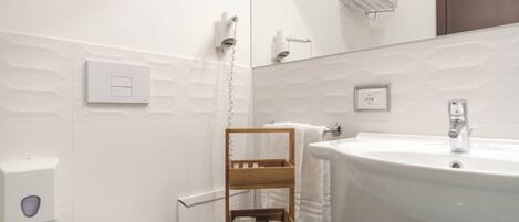 Une salle de bain moderne avec un lavabo blanc, un porte-serviettes en bois et des toilettes.