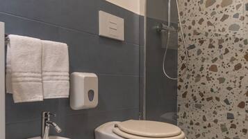 Une salle de bain équipée d’un bidet, de toilettes et d’une douche.