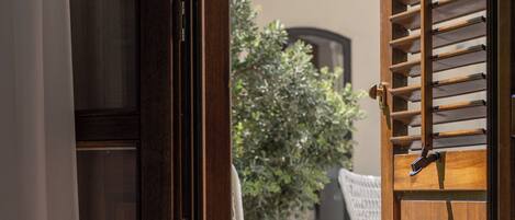 Une porte en bois, dotée d’un loquet, qui donne sur un espace extérieur aménagé avec une chaise et une table blanches.