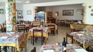A dining area with multiple tables and chairs, decorated with patterned tablecloths. - Villa Al Parco (FORIO)