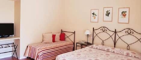 A bedroom with two beds, a TV, and framed pictures on the wall.