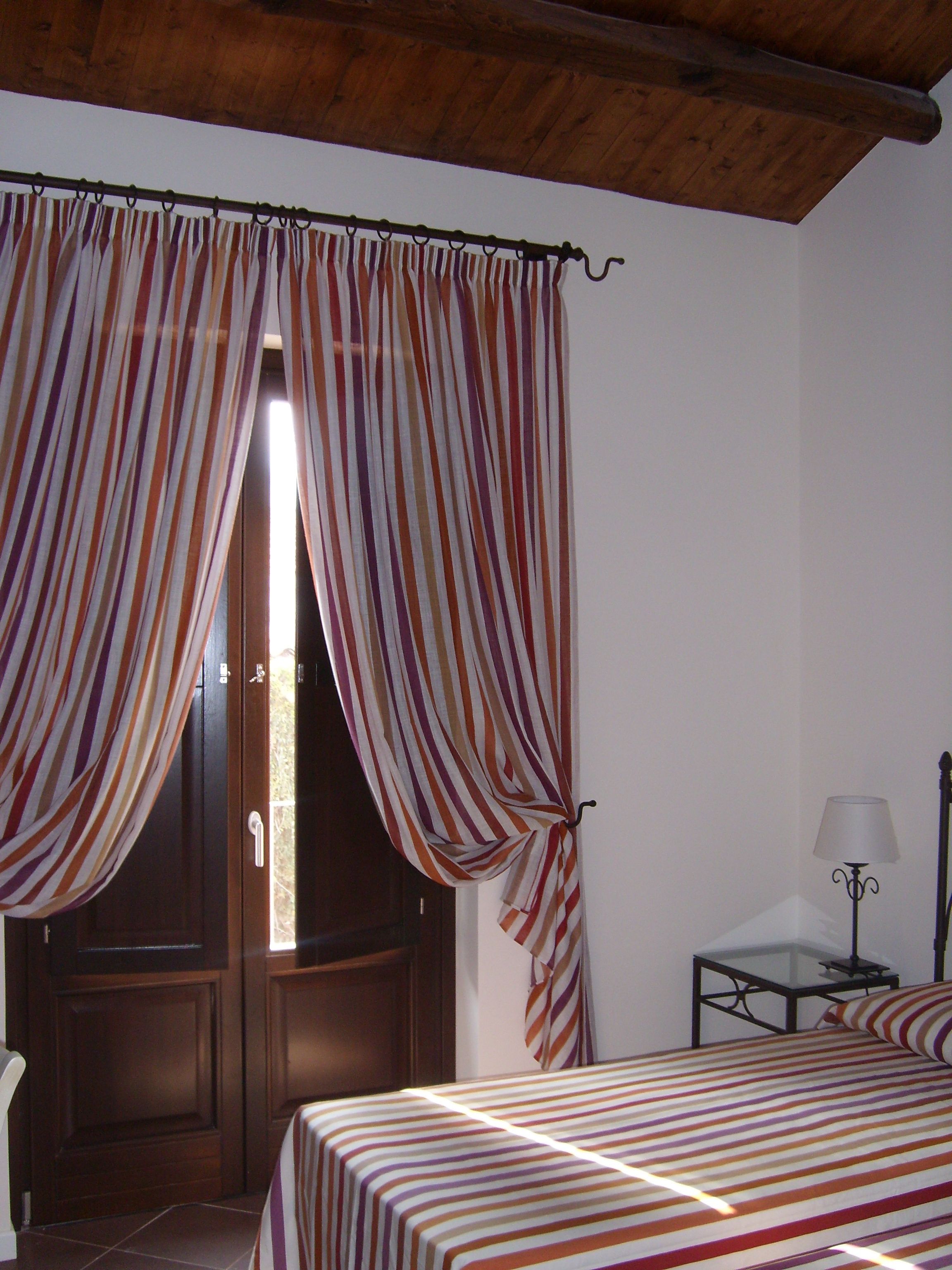 A room with a bed, a nightstand, a lamp, and curtains.