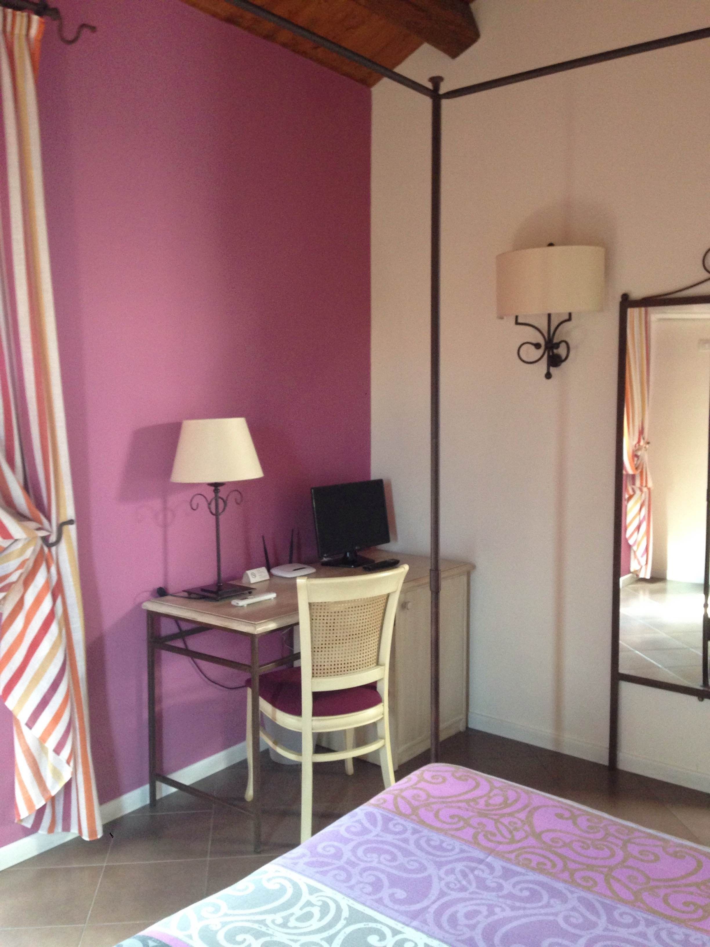 A room with a bed, a desk with a computer, a chair, a lamp, and a mirror.