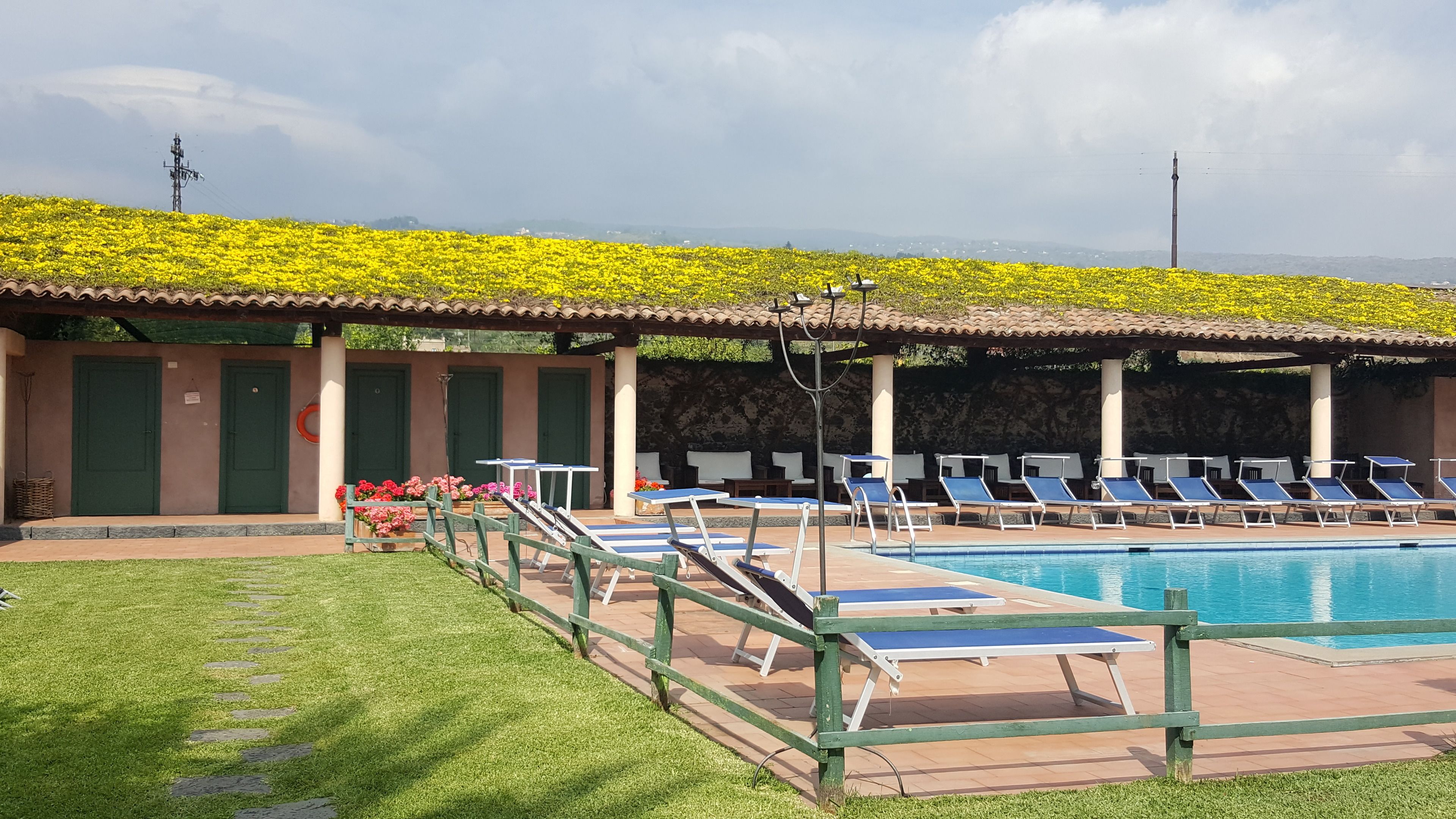 Un área junto a la piscina con sillones de descanso y una pileta.