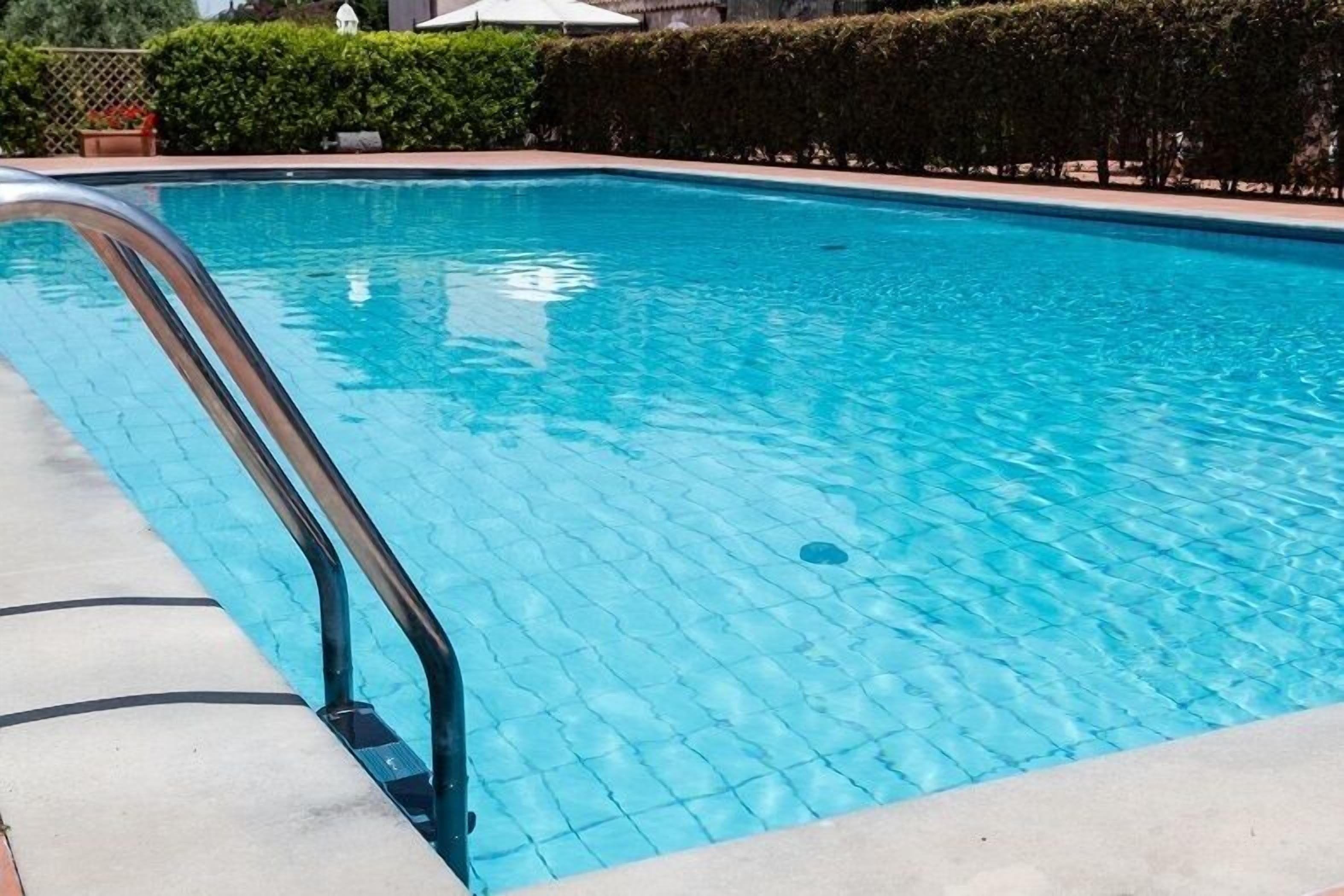 Una piscina con solárium de azulejos y barandillas metálicas.
