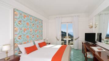 Una camera d'albergo con un letto, una TV, una scrivania e vista sul mare.