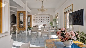 A spacious living room with a chandelier, a sofa, a coffee table, and a TV.