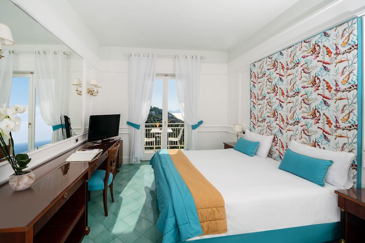 Une chambre d’hôtel équipée d’un lit, d’un bureau, d’une télévision et offrant une vue sur l’extérieur.