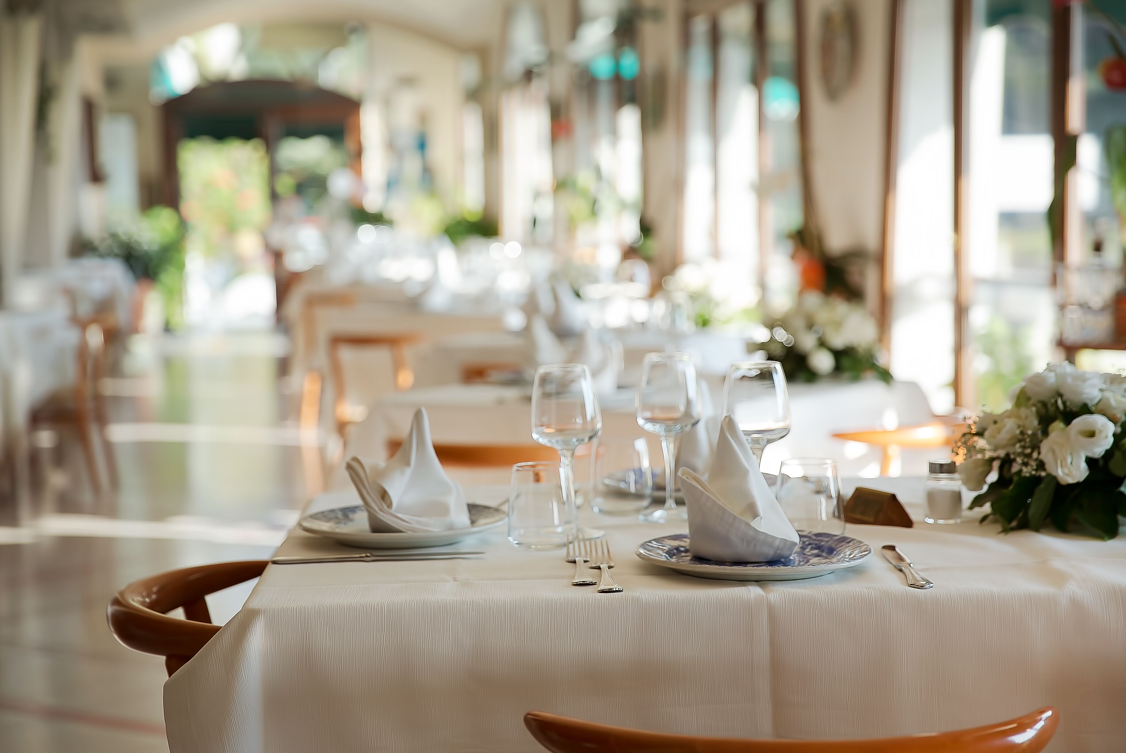 Un espace repas avec des tables dressées pour le service, agrémenté de nappes blanches et de couverts disposés avec soin.