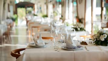 Un espace repas avec des tables dressées pour le service, agrémenté de nappes blanches et de couverts disposés avec soin.