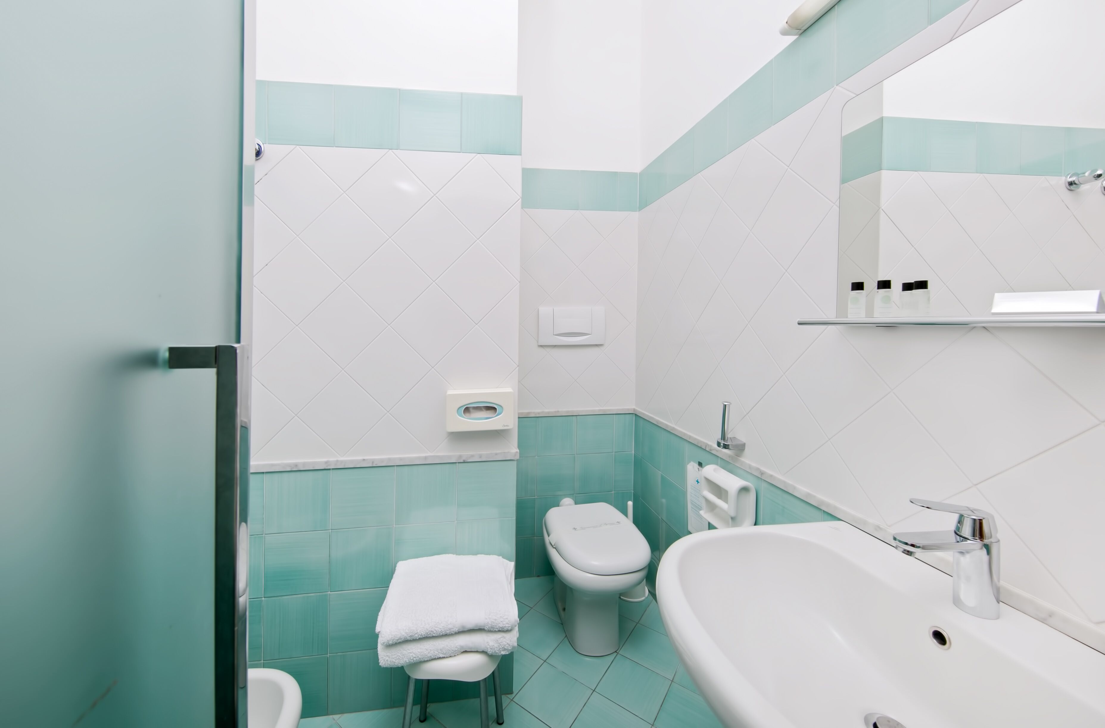 A bathroom with a toilet, sink, and a towel rack.