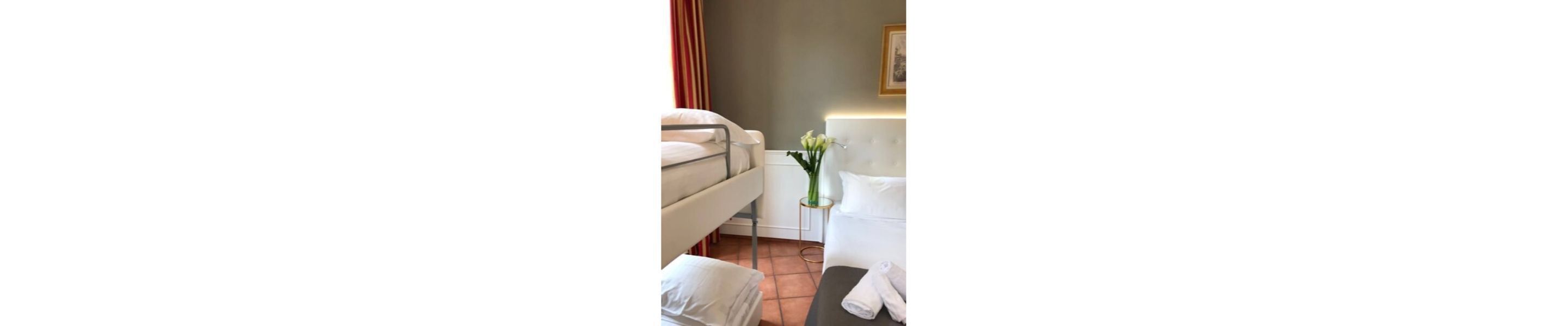 Una habitación de hotel con una cama, una mesita de noche con un jarrón de flores y una silla.