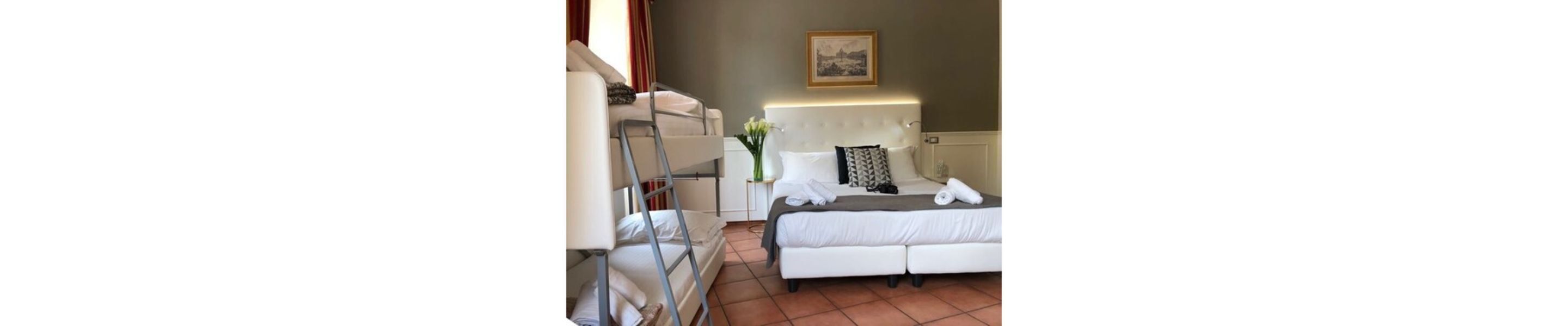 Ein Hotelzimmer mit Bett, Nachttisch, Lampe und einem Fenster mit Vorhängen.