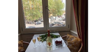 A dining table set with a bottle, a glass, and a plate of food, with a window view of a street and parked cars. - 207 Inn (Rome)