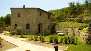 A stone building with a small garden, a wooden bridge, and a stone wall.