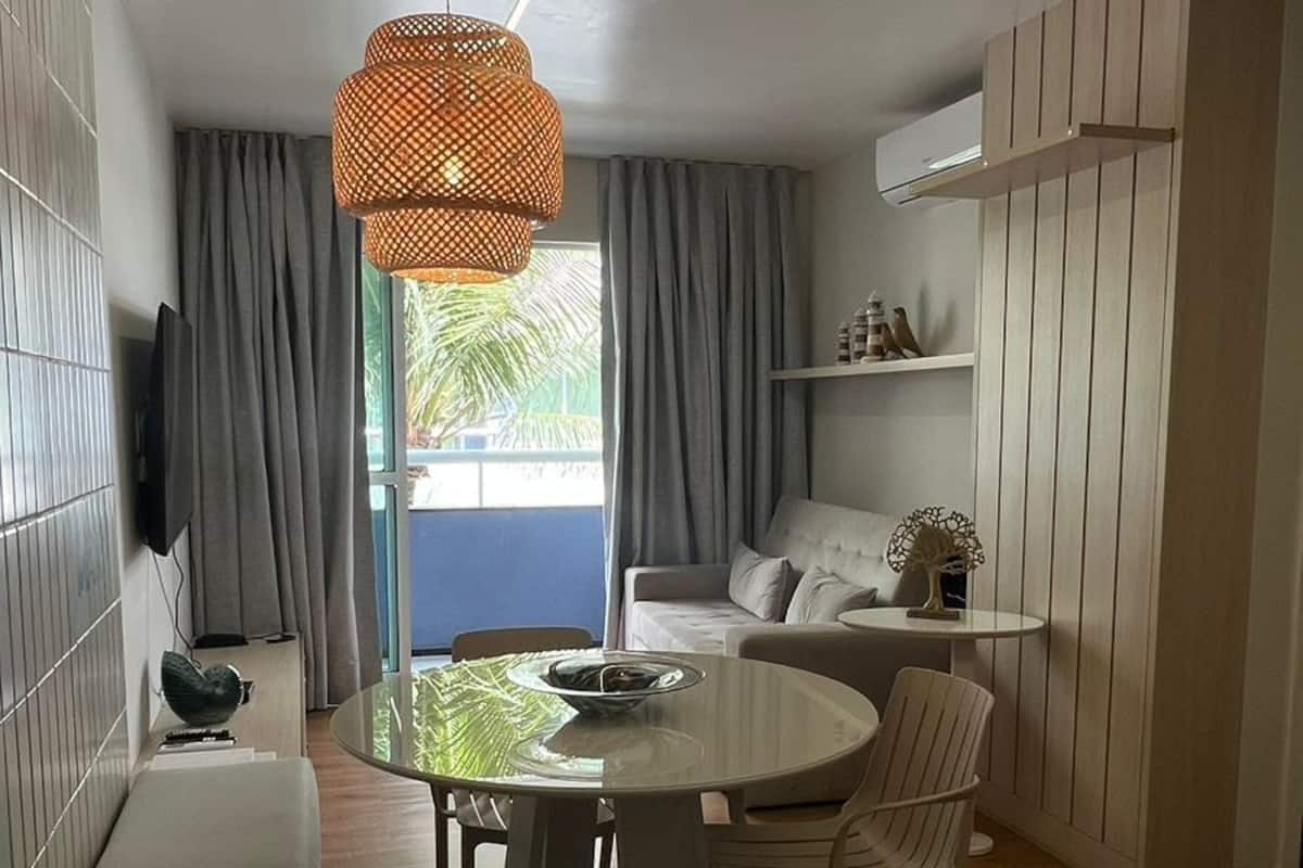 A modern living room with a round glass table, white chairs, a sofa, and a hanging light fixture.